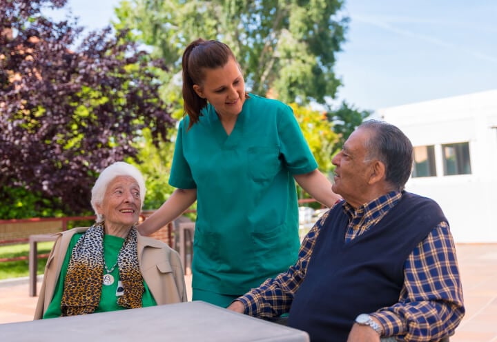 Elderly Couple Being Assisted by a Female Nurse Outdoors of Assisted Living Facility Elderly Couple Being Assisted by a Female Nurse Outdoors of Assisted Living Facility